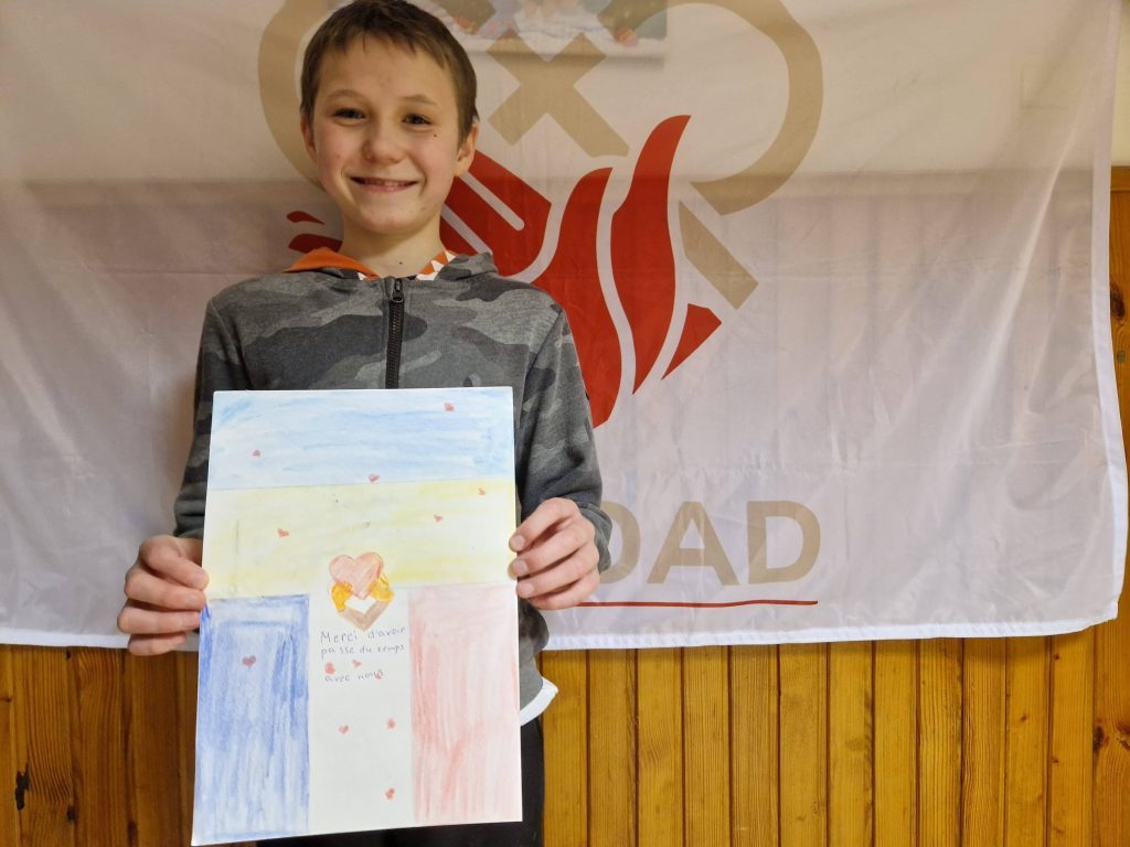 Un petit garçon pose avec son dessin pour Caridad
