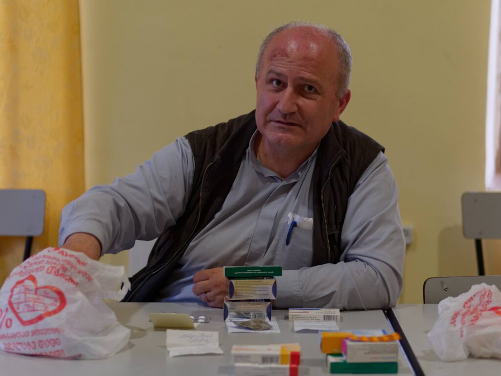 Le père Akaki distribuant des médicaments.